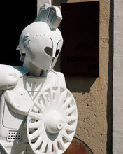 Load image into Gallery viewer, Outdoor detail of Plastic Apocalypse – Trojan Warrior beside the Scoobafish Art studio sign, showing its helmet and circular shield.