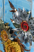 Load image into Gallery viewer, Vertical close-up of Sunflowers III by Scoobafish, featuring a silver recycled-metal sunflower with a red mechanical centre, surrounded by copper and metal leaves on a blue painted panel.
