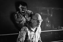 Load image into Gallery viewer, Black-and-white portrait of artist Scoobafish in front of My Name Is Muhammad, with the sculpted figure of Muhammad Ali behind him.
